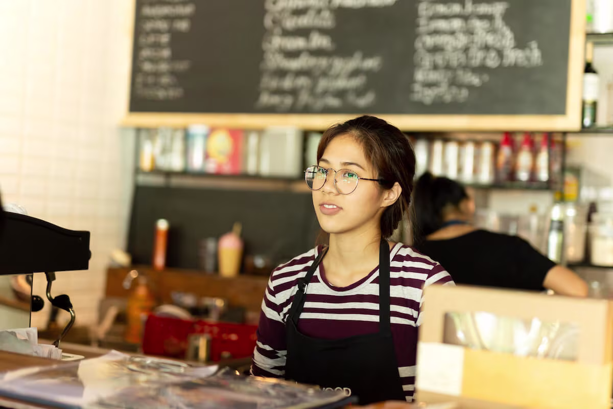 A server stands behind the counter at a cafe during her shift