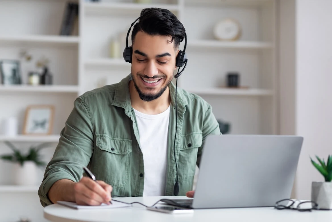 Man wearing headphones while taking notes