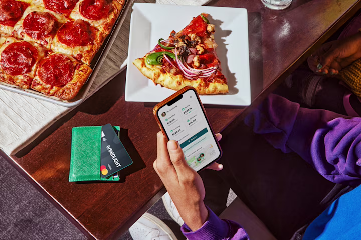 Hand holding phone with GL app showing above table with pizza slice