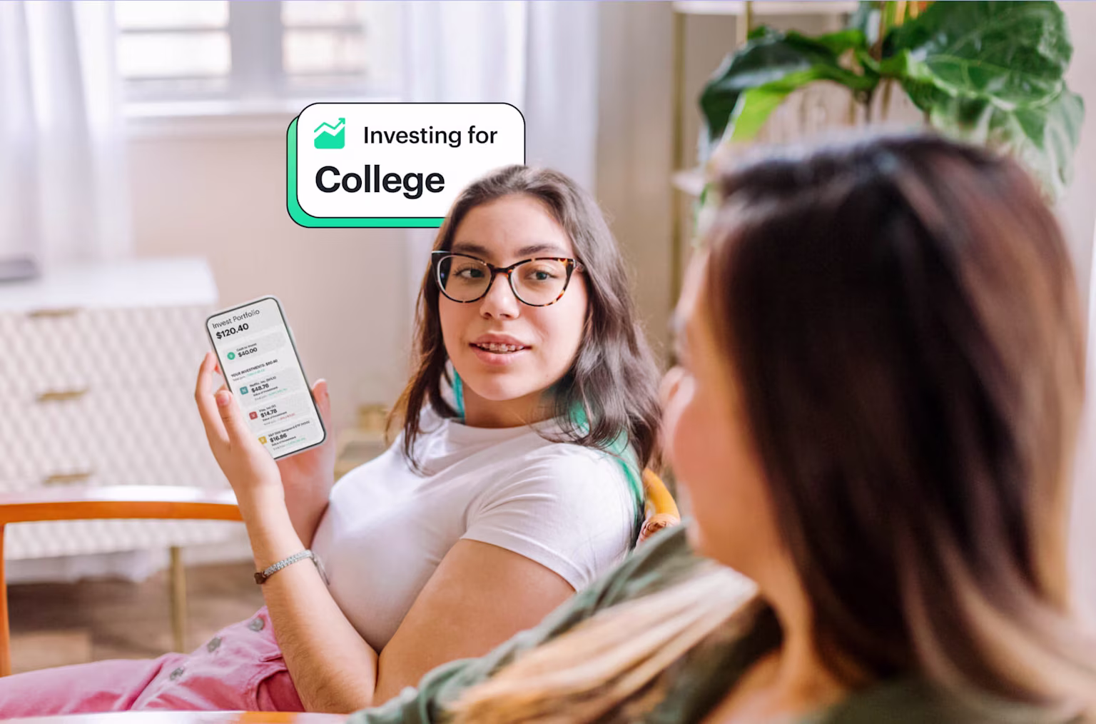 Teen girl showing mom how she's investing for college with money earned from her job with Greenlight app