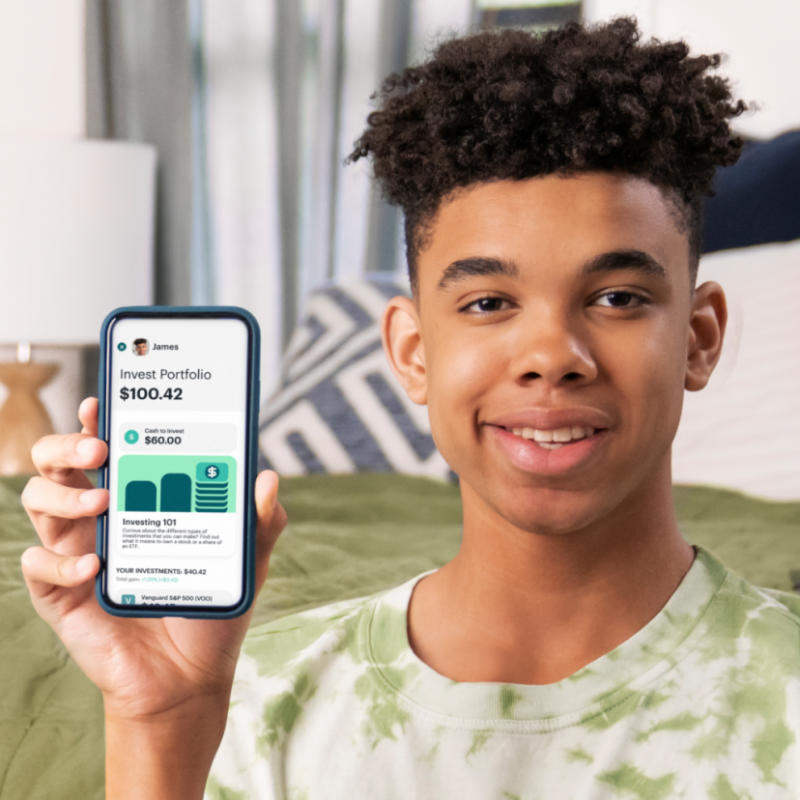 teen boy holding his phone with the greenlight investing profile showing