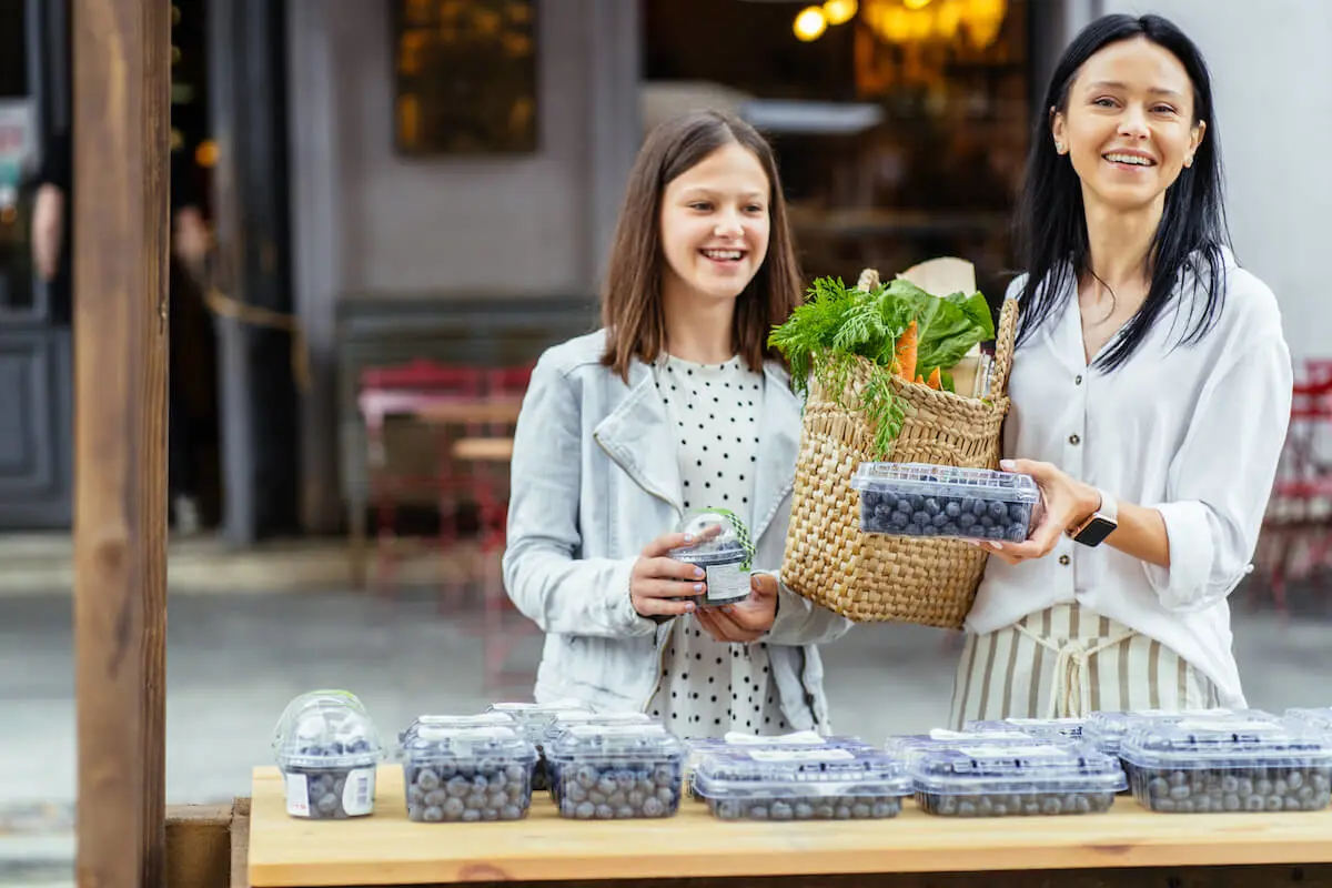 Mother and daughter buying blueberries