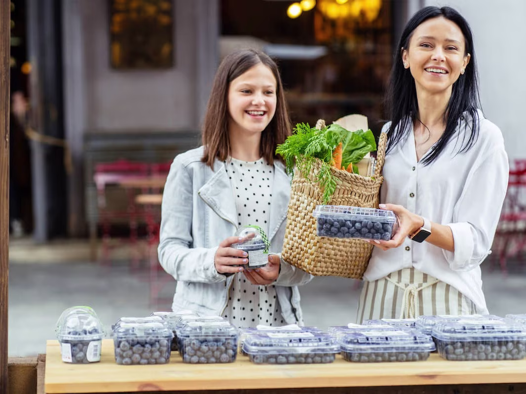 Mother and daughter buying blueberries