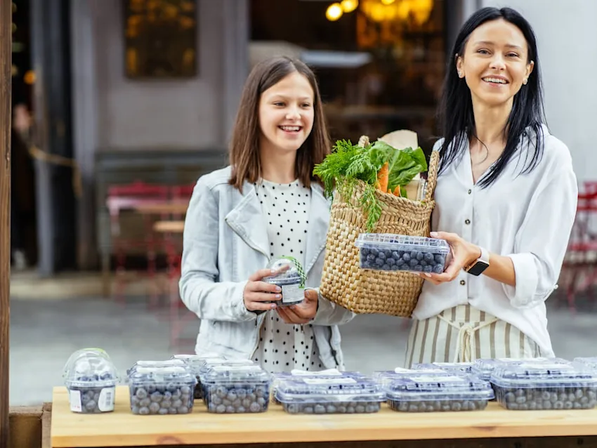 Mother and daughter buying blueberries