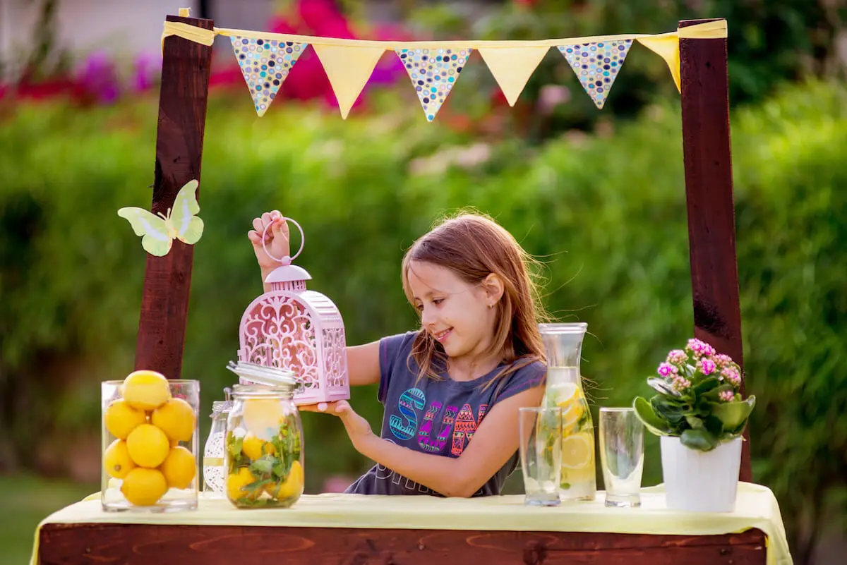 How to make money from home as a kid: little girl manning her lemonade stand