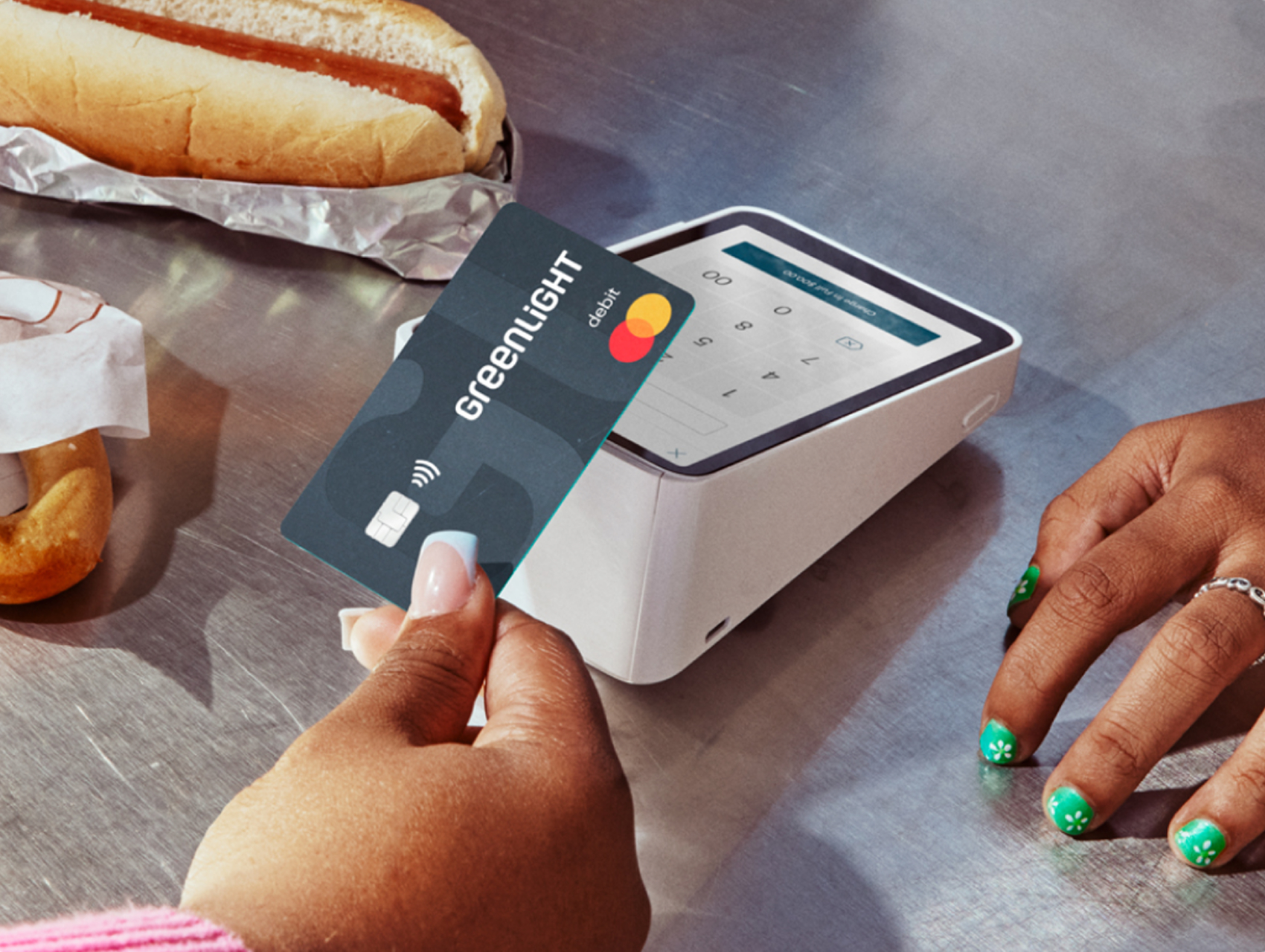 Image of a teenage girl's hand tapping her Greenlight card at a concession stand