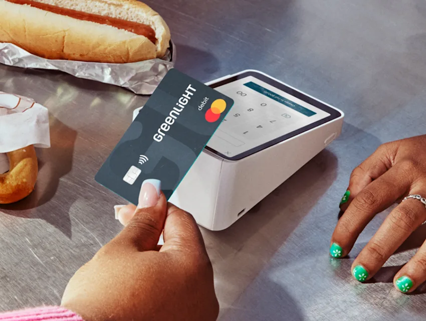 Image of a teenage girl's hand tapping her Greenlight card at a concession stand
