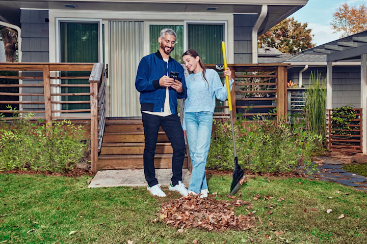 Dad and daughter raking leaves in front of house.