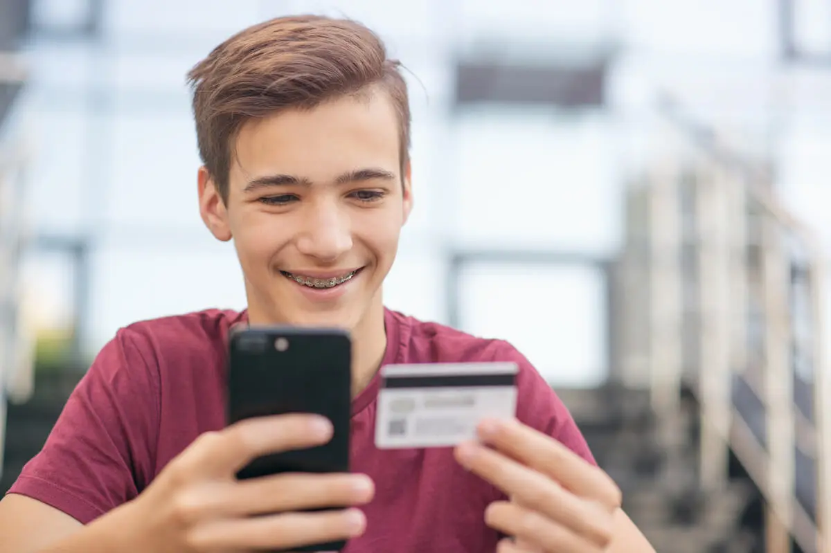 Teenager with braces holding a card and a phone