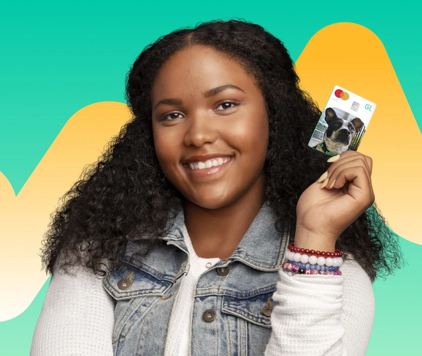 Teen girl holding Greenlight debit card, color background