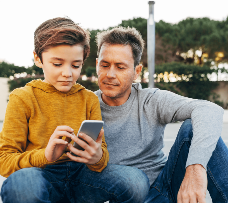 young boy looking at a smartphone next to his father