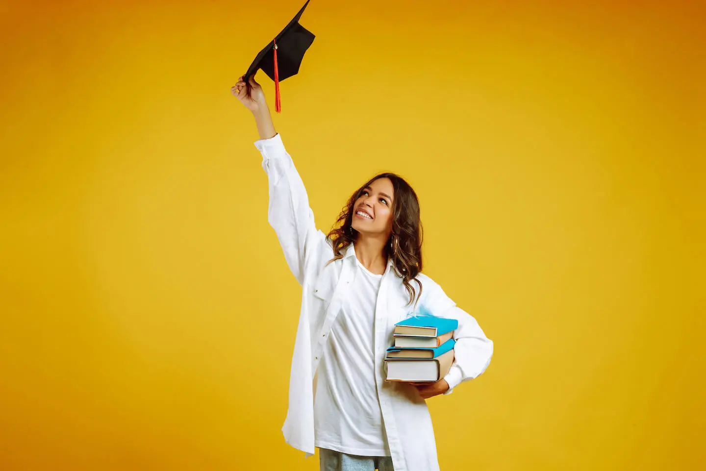 How to prepare for college: student carrying some books and holding a graduation cap