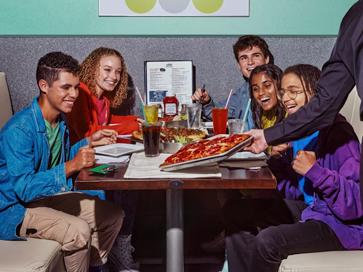 Kids at a diner ordering a pizza with their Greenlight card