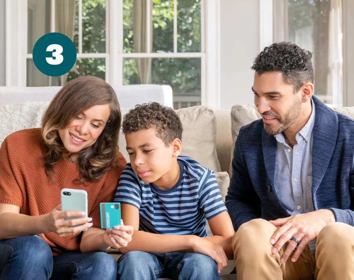 boy with his parents and a greenlight debit card