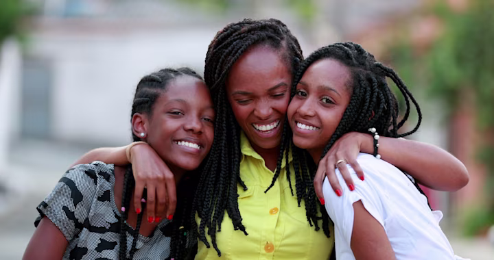 Mom and siblings hugging each other while smiling.