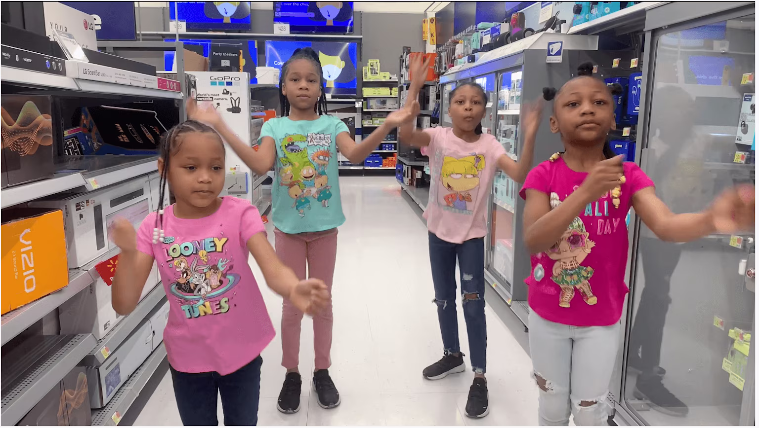 young girls dancing in the electronic aisle of a store