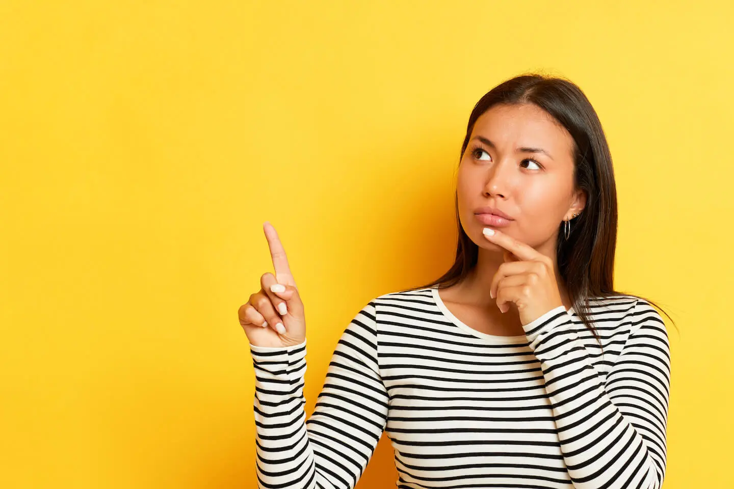 Woman thinking while pointing her finger upwards