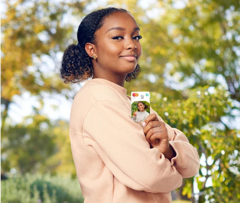 teenage girl outside holding a greenlight custom debit card