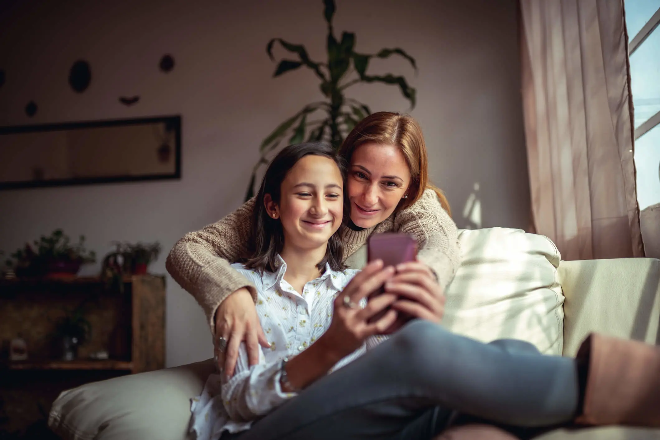 mom and daughter looking at her smartphone smiling