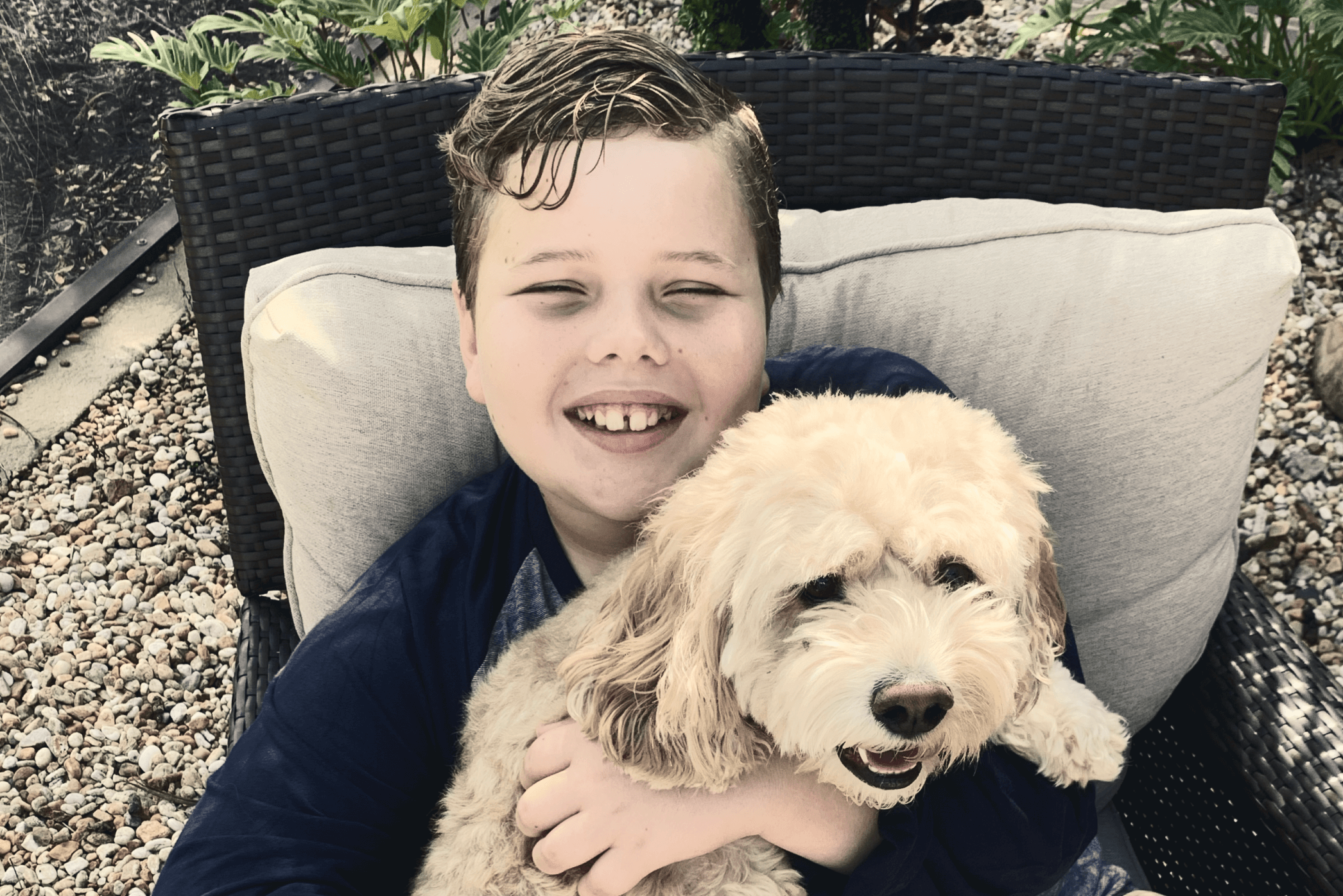 young boy smiling while he holds his dog