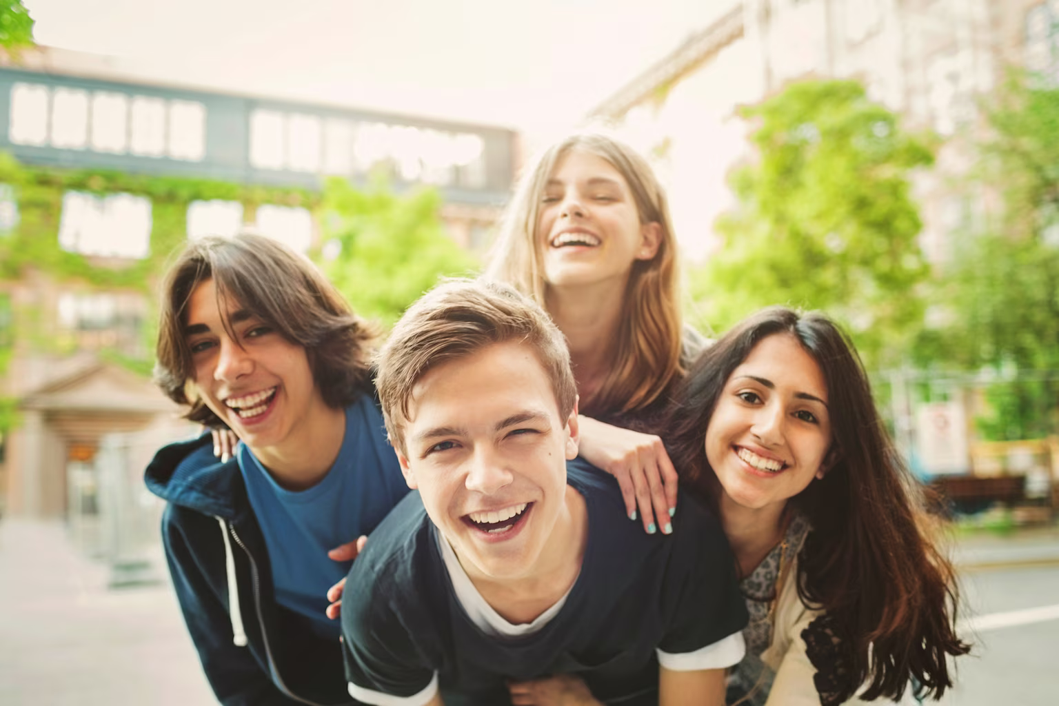 Group of friends outside laughing and looking at camera.