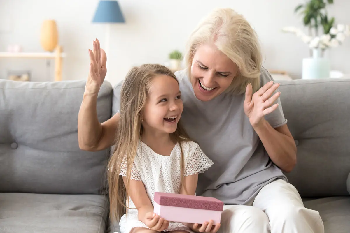 Stocks as gifts: little girl happily opening a gift with her grandmother