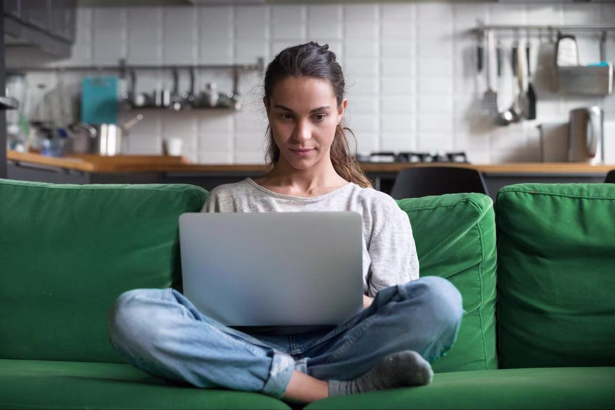 Woman using a laptop while sitting on a couch