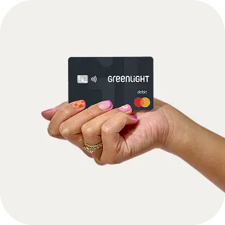 Woman's hand holding a Greenlight debit card