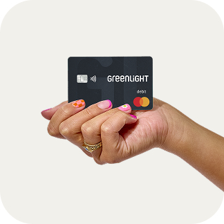 Woman's hand holding a Greenlight debit card