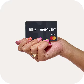 Woman's hand holding a Greenlight debit card