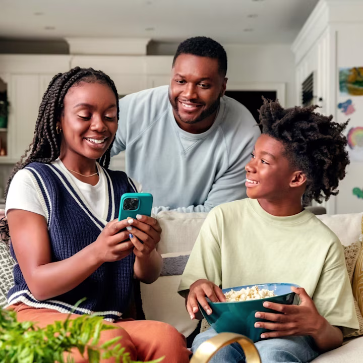 Father with son and daughter happy looking at the cellphone on a couch