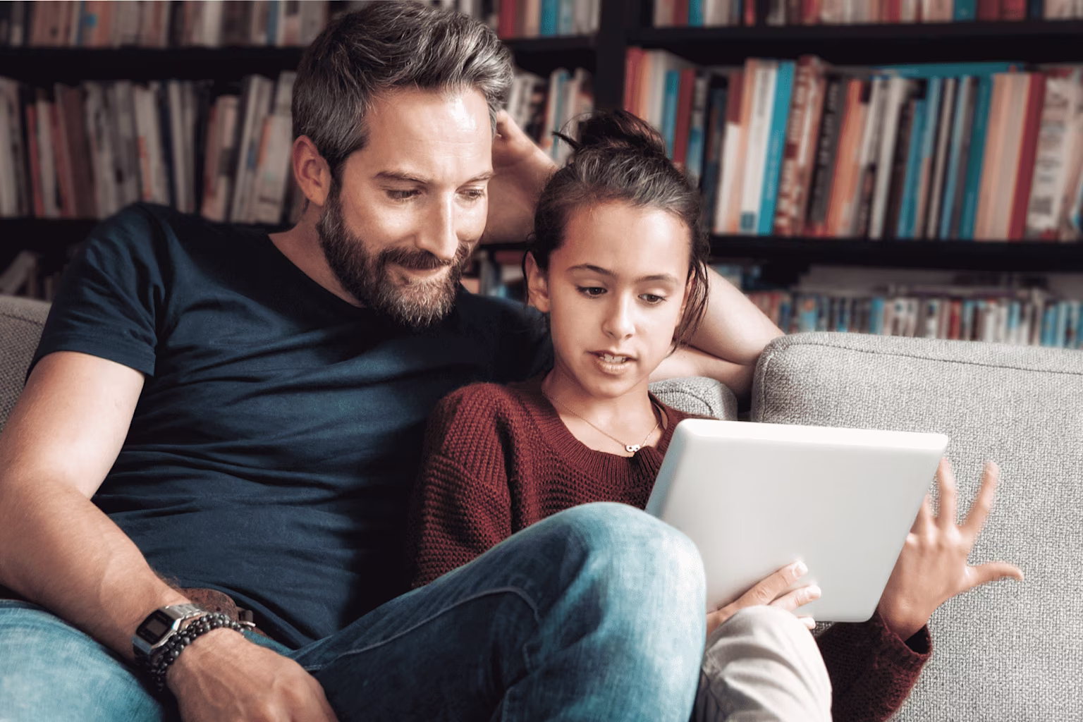Young girl and father learning about stocks on tablet with Greenlight’s investing app