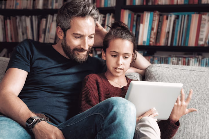 Young girl and father learning about stocks on tablet with Greenlight’s investing app