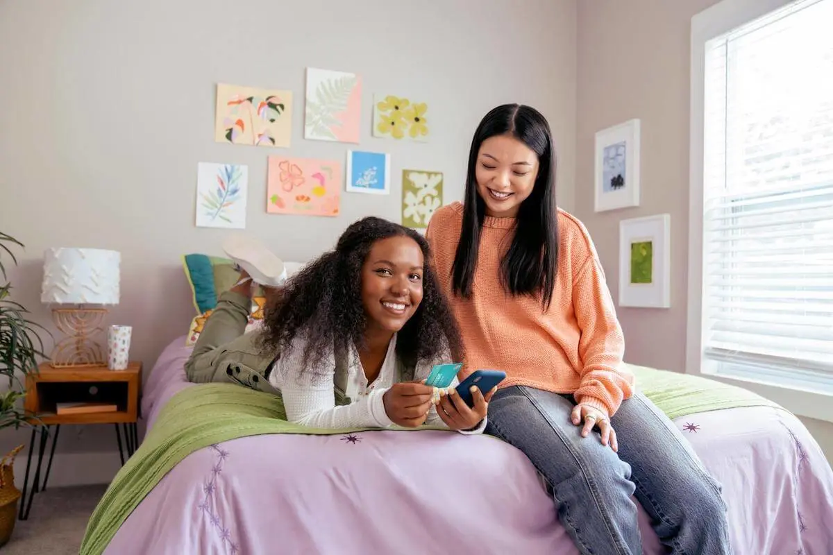 Friends using a phone and holding a credit card