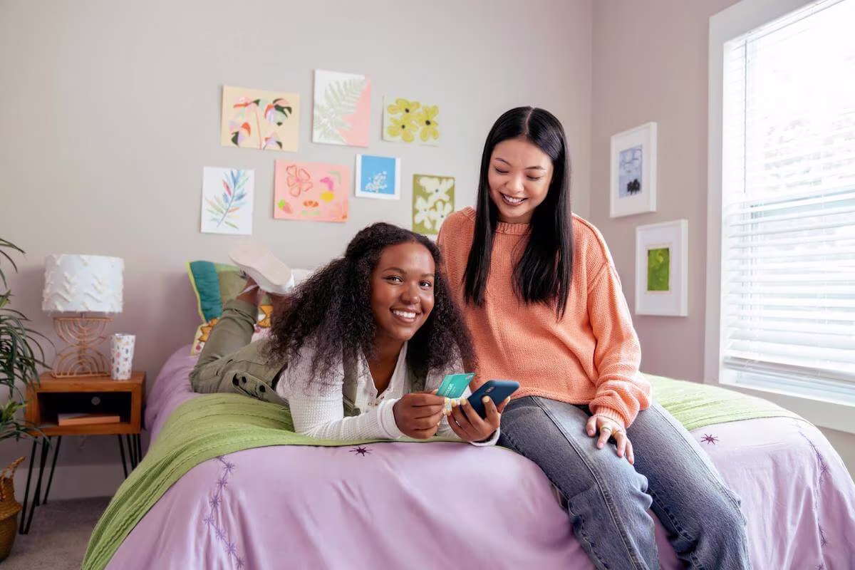 Friends using a phone and holding a credit card