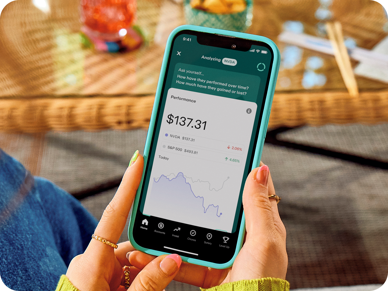 Person holding turquoise phone displaying investment app with NVDA stock performance at $137.31 and performance graph.