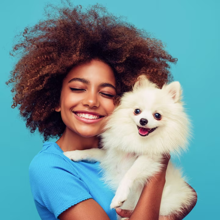 Should I get a dog? Teen girl holds furry white dog close to her while smiling