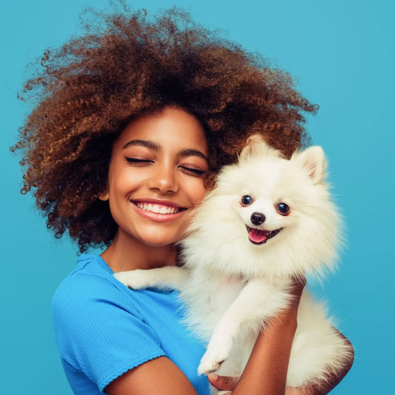 Should I get a dog? Teen girl holds furry white dog close to her while smiling