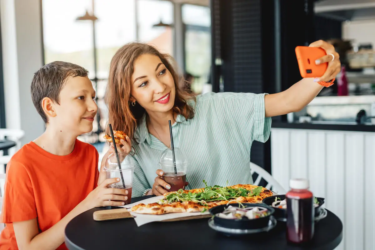 Mother and her kid taking a groufie at a restaurant