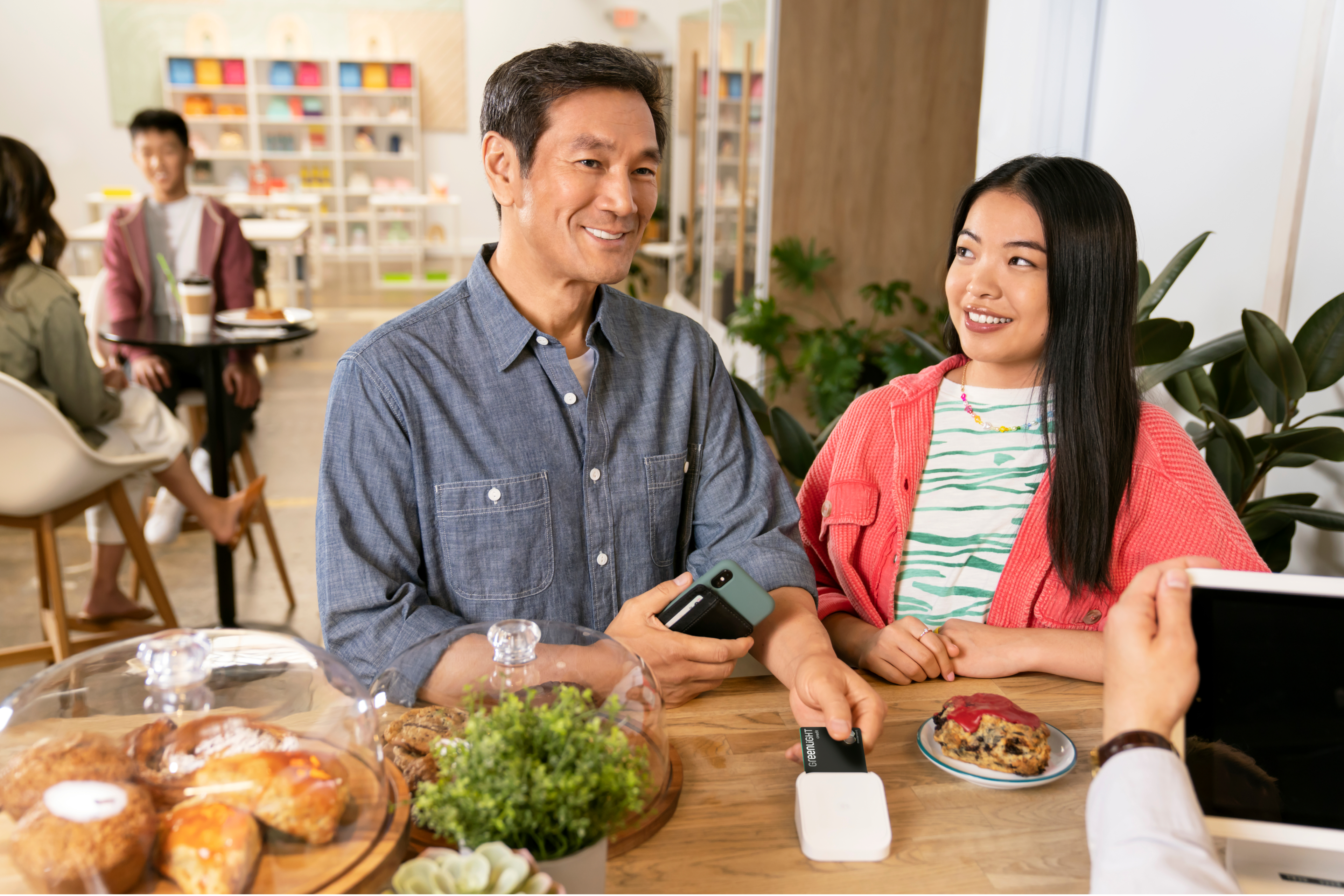 Father and daughter paying with their Greenlight parent credit card at a coffee shop while similing