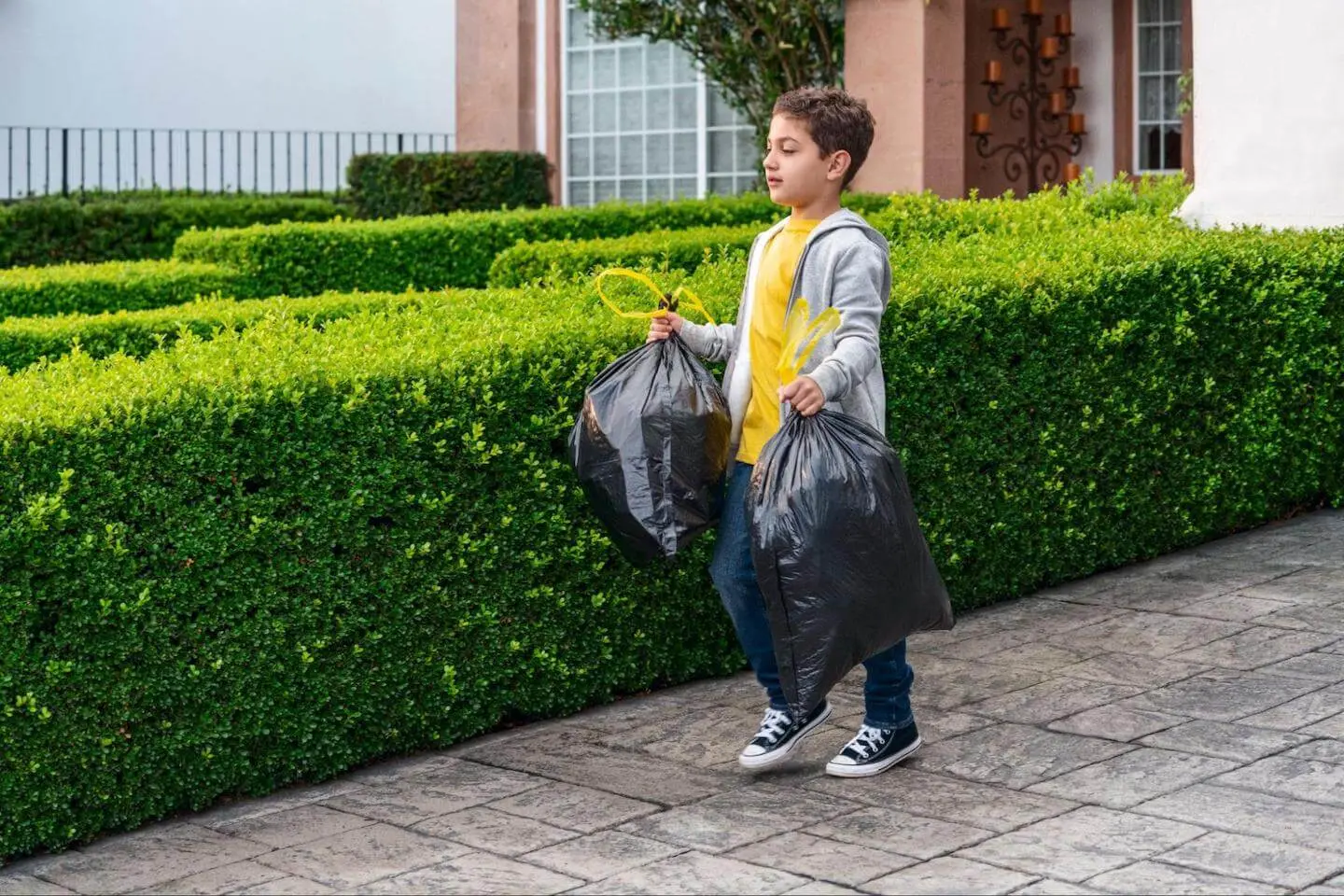 Jobs for 11 year olds: boy carrying 2 trash bags
