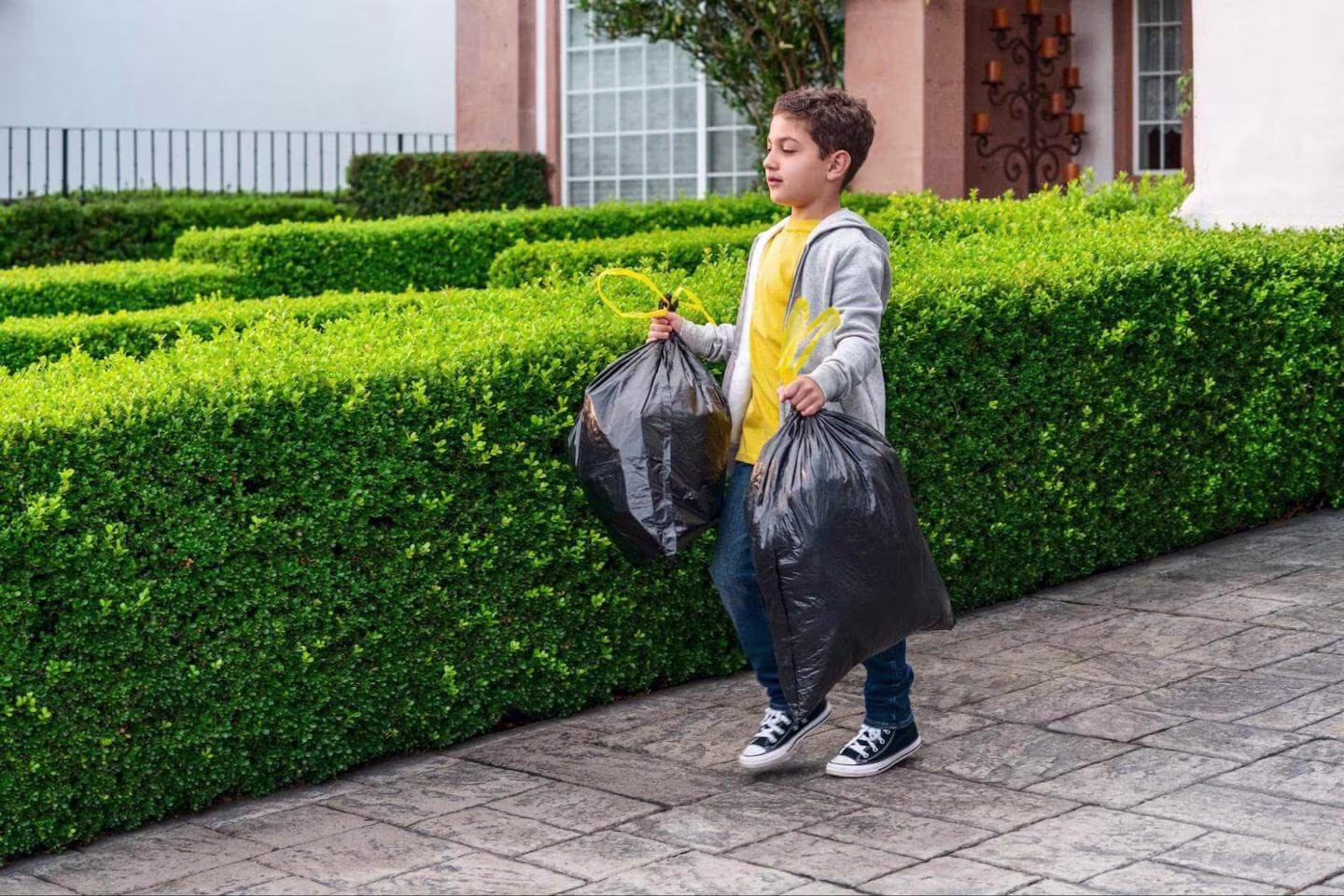 Jobs for 11 year olds: boy carrying 2 trash bags