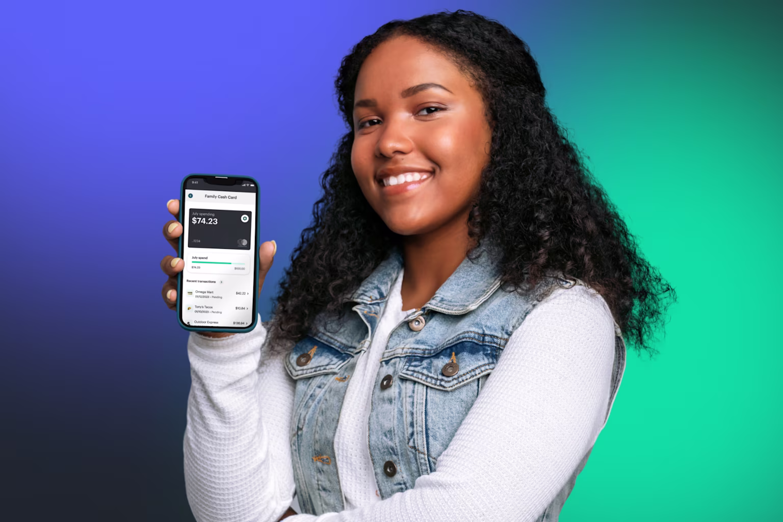 Teen girl showing mobile money app with Greenlight teen credit builder