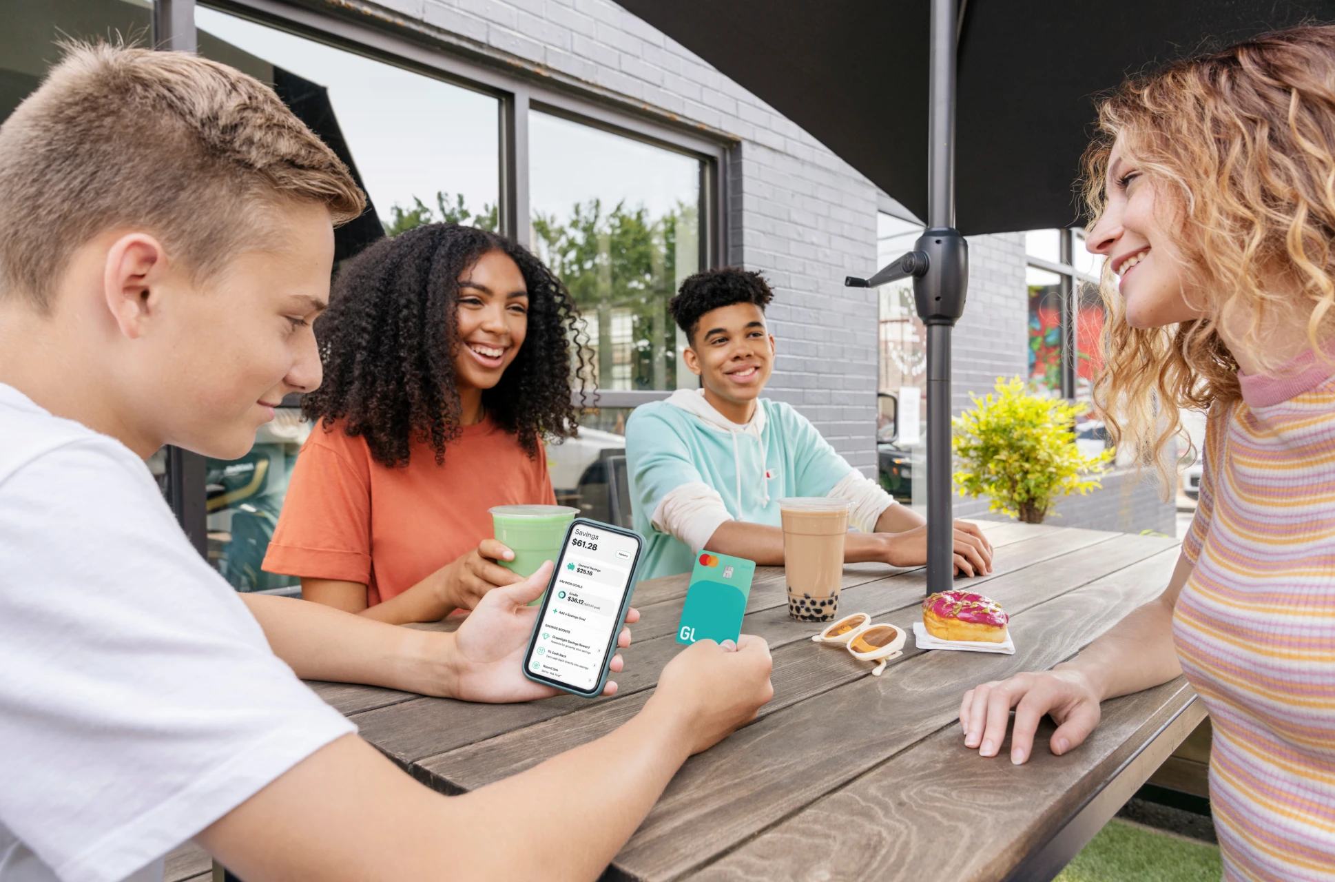Teens hanging out around an outdoor table discussing their futures with the Greenlight investing app