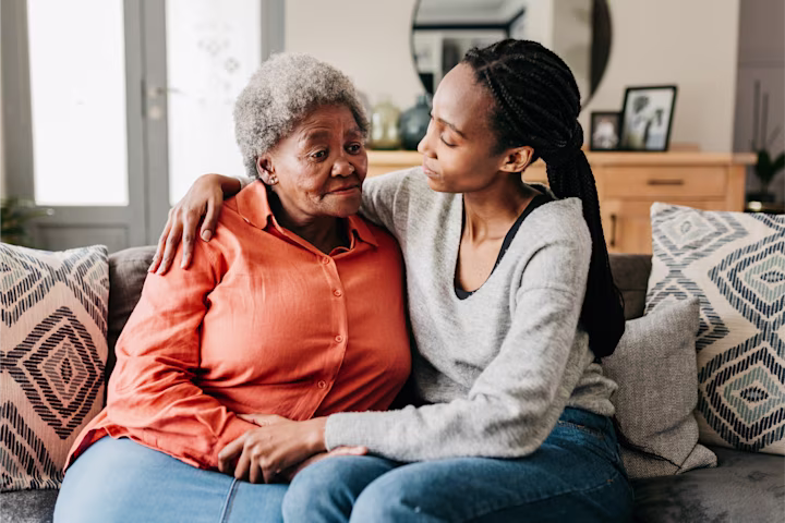 Two woman embracing while sitting on couch