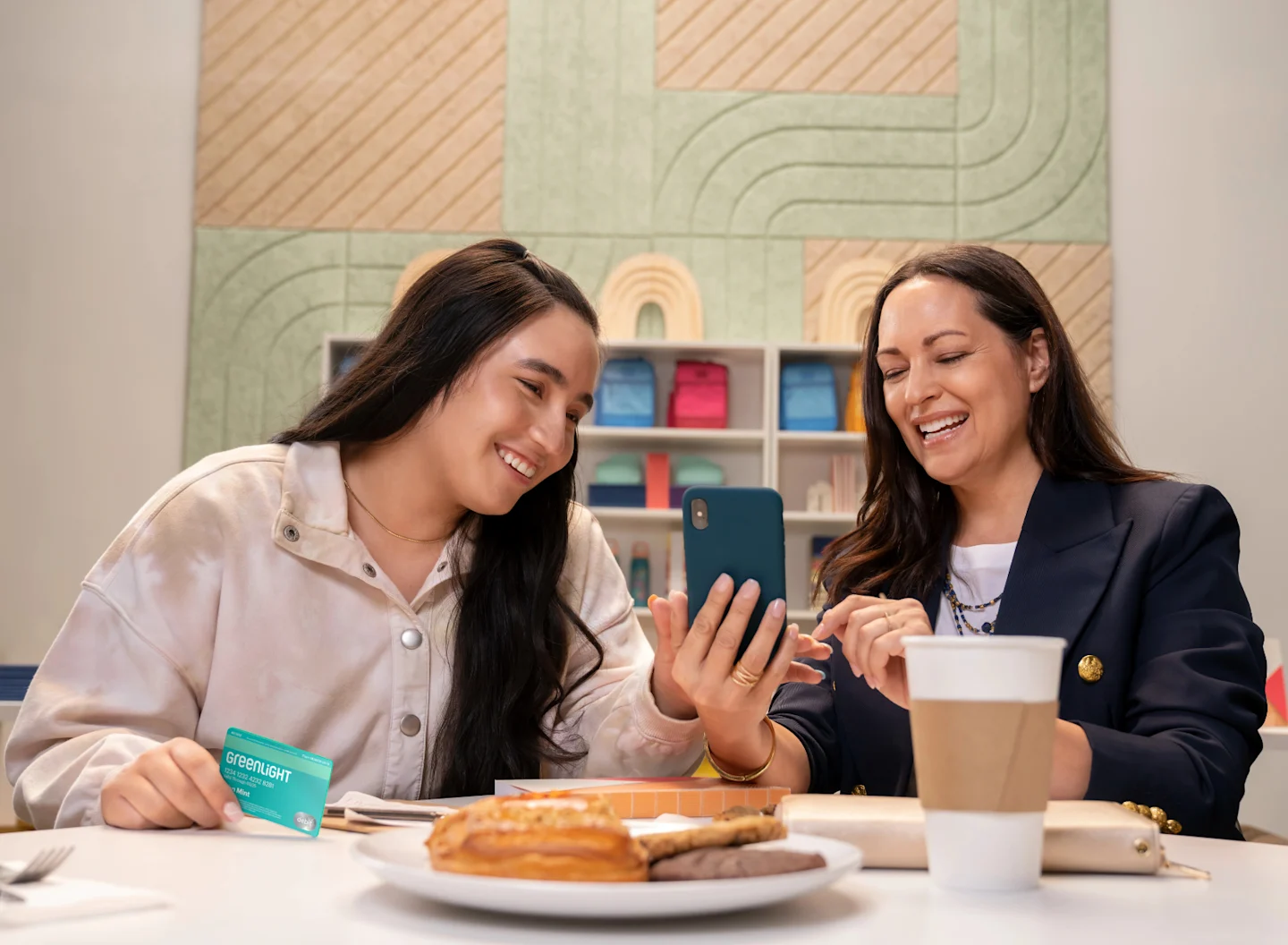 Mom and daughter look at phone at a kitchen table
