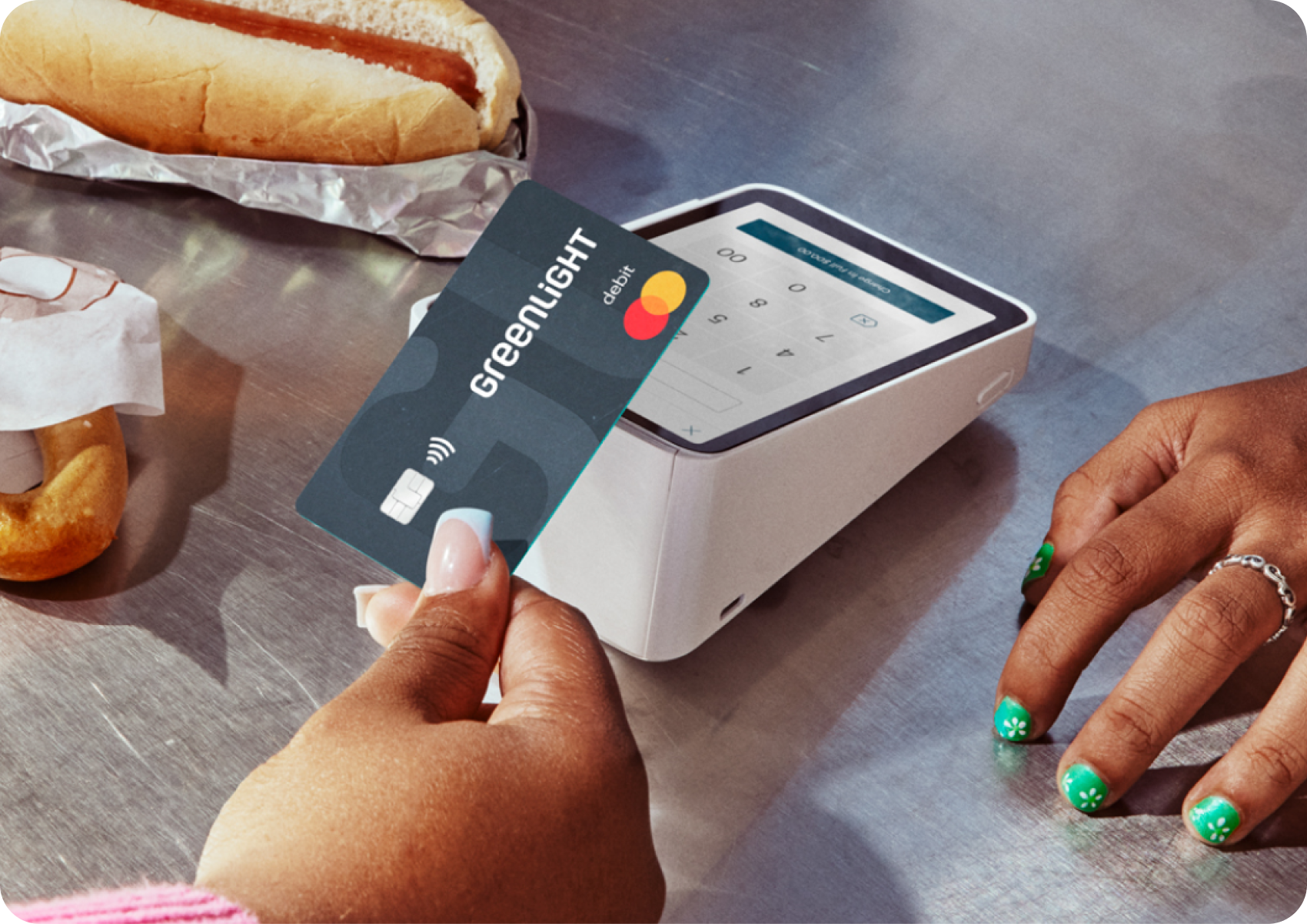 Woman holding a Greenlight card tapping it at a card terminal