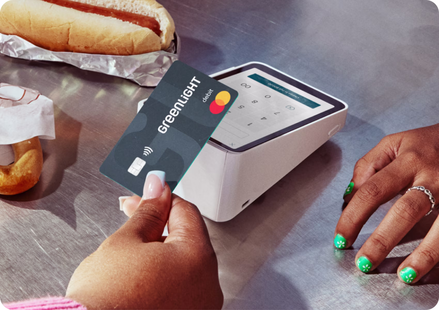 Woman holding a Greenlight card tapping it at a card terminal