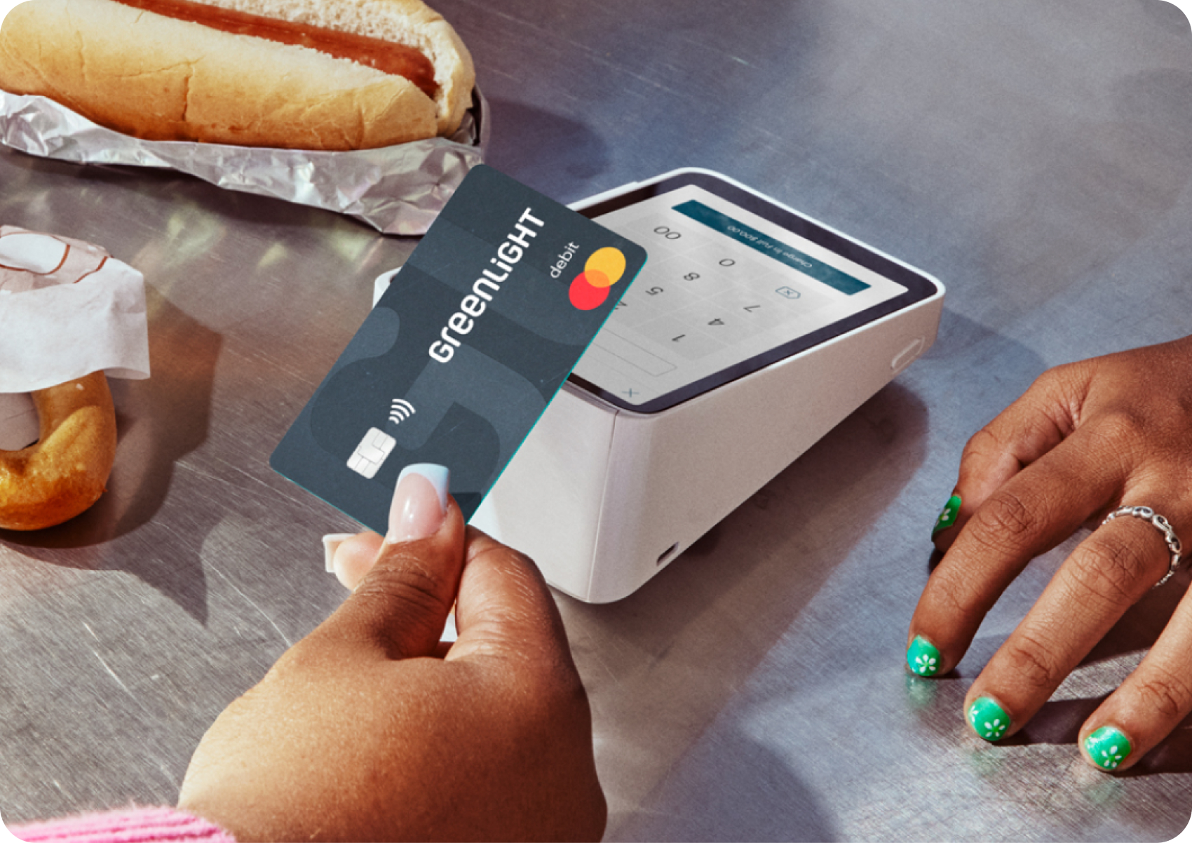 Woman holding a Greenlight card tapping it at a card terminal
