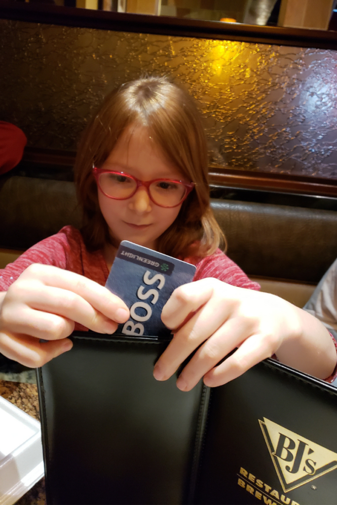 young girl paying for her meal with her Greenlight debit card for kids